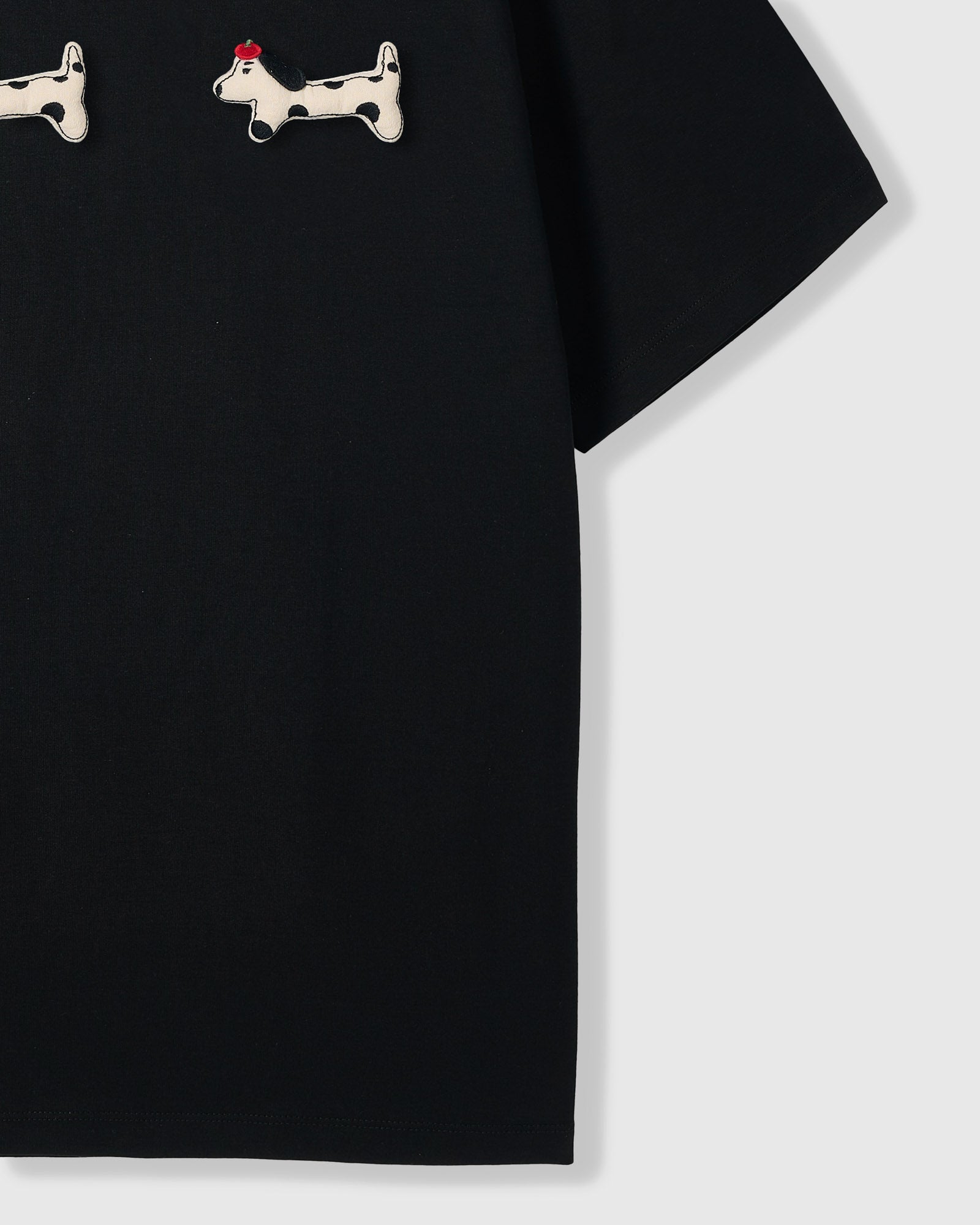 {{Rated 4.9 by thousands}} Spotted dachshund plush appliqué detail showing hand-stitched craft on STICKYZOO black t-shirt