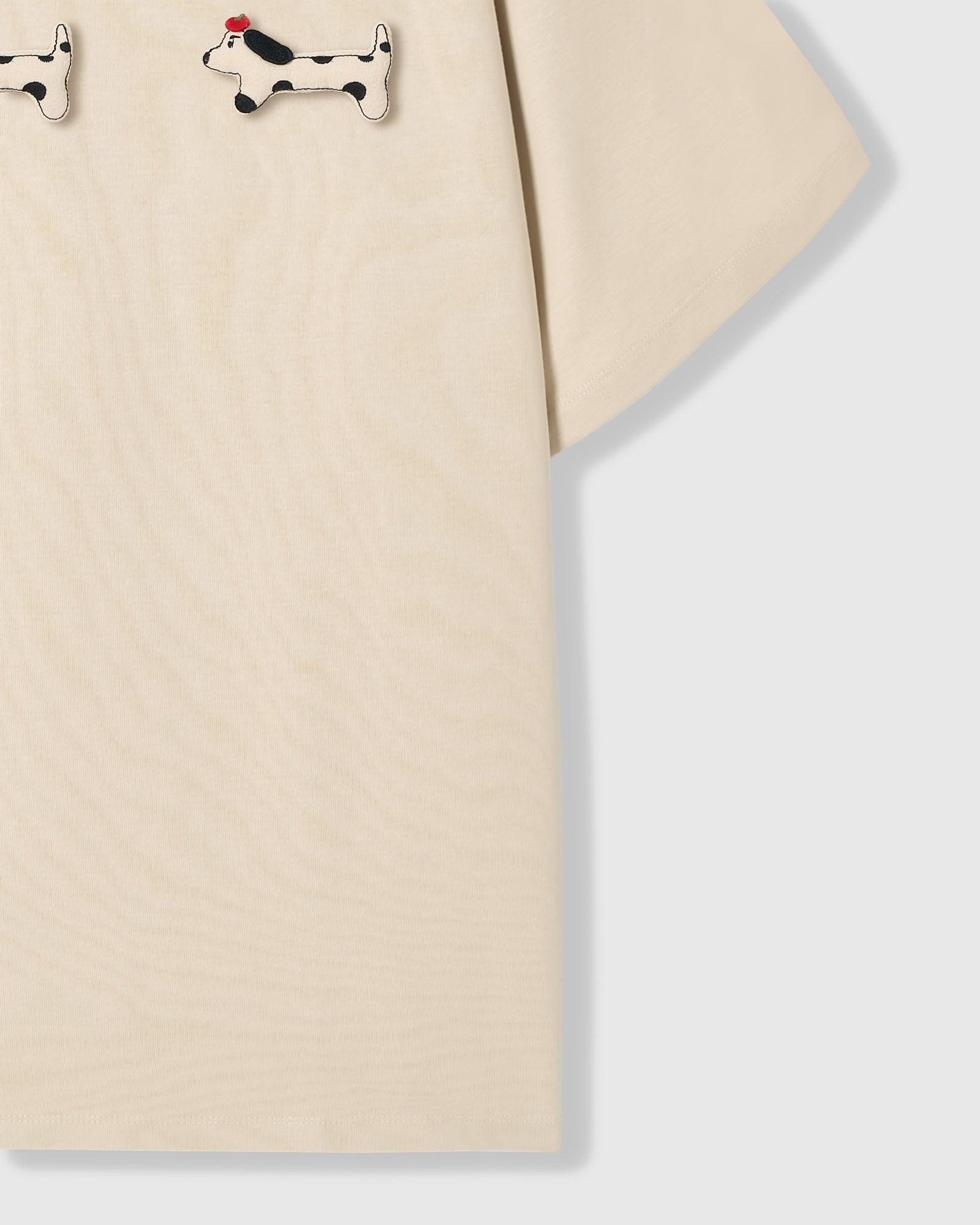 Spotted dachshund plush appliqué detail showing hand-stitched craft on STICKYZOO cream t-shirt