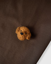 Macro close-up of single plush poodle face on brown 230gsm cotton showing curly 3D texture