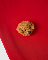 Macro close-up of single plush poodle face on red 230gsm cotton showing curly 3D texture