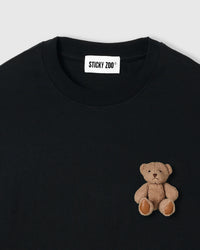 Close-up of plush teddy bear applique on black 230gsm cotton showing 3D layered texture and embroidered eyes