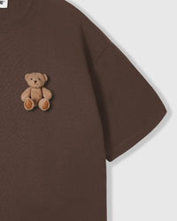 Close-up angle of hand-stitched sitting teddy bear on 230gsm cool-touch cotton in dark brown