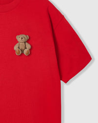 Close-up of sitting teddy bear with leather-tone paw pads on red cotton