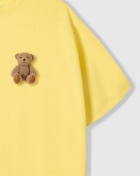 Close-up of seated teddy bear applique near sleeve showing stuffed dimensional texture and paw detail
