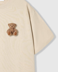 Close-up of second plush teddy bear near hem on cream cotton