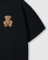 Close-up of sitting teddy bear applique with contrasting paw pads on black cotton