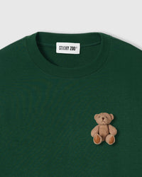 Close-up of sitting teddy bear applique on forest green 230gsm cotton showing plush layered construction