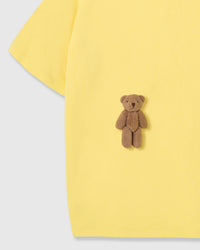 Close-up of second plush teddy bear near hem on lemon cotton showing hand-stitched detail