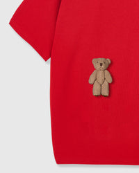 Detail of standing teddy bear applique against bold red cotton base showing dimensional construction