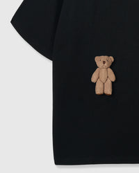 Detail of standing teddy bear on black cotton showing dimensional hand-stitched plush construction