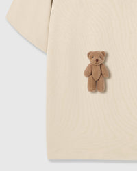 Both seated teddy bear appliques on cream fabric showing dimensional texture and placement
