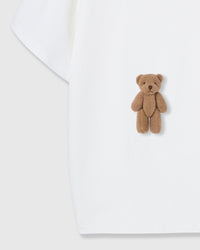 Close-up of second plush teddy bear near hem on white cotton