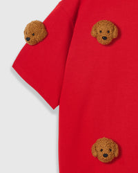 Close-up of shoulder area on red tee showing plush poodle placement and dropped sleeve