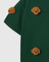 Close-up of shoulder area on green tee showing plush poodle placement and dropped sleeve