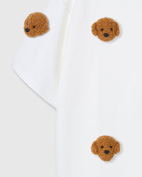 Close-up of shoulder area on white tee showing plush poodle placement and dropped sleeve