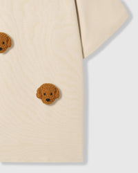 Detail of lower body area on cream Poodle Parade T-Shirt showing plush poodle appliques