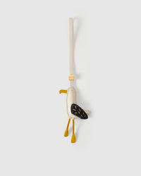 Seagull charm handmade from French Alran genuine goatskin — cream body, black wing with yellow stitched feather dashes, yellow beak, dangling yellow legs, cream leather strap. Three days by hand. Arrives in luxury gift packaging. Designed in Amsterdam.