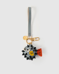 Both editions of the pufferfish charm — leather strap loop for bags, or 18K gold-plated keychain clip.