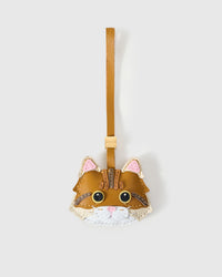 Ginger Maine Coon cat charm handmade from French Alran genuine goatskin — caramel-orange body, brown forehead stripes, gold eyes, pink heart nose, white chin, tan leather strap. Three days by hand. Arrives in luxury gift packaging. Designed in Amsterdam.