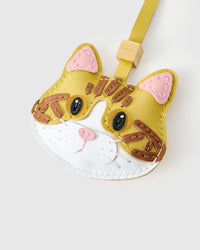 Both editions of the yellow-strap tabby cat charm side by side — leather strap loop for bags, or 18K gold-plated keychain clip with engraved STICKYZOO disc.