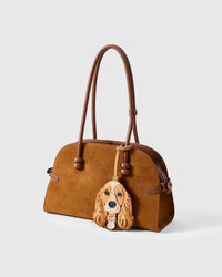 Handmade Cocker Spaniel leather bag charm on a brown suede handbag — full-grain French Alran leather and suede, hand-layered, hand-stitched. STICKYZOO collectible, designed in Amsterdam.