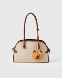 Handmade Chow Chow leather bag charm shown on a cream canvas handbag — full-grain French Alran goatskin and suede, hand-layered fluffy mane. STICKYZOO collectible.