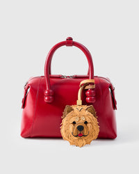 Handmade Chow Chow leather bag charm on a red leather handbag — built to last from French Alran leather and suede, hand-layered, hand-stitched. STICKYZOO collectible.