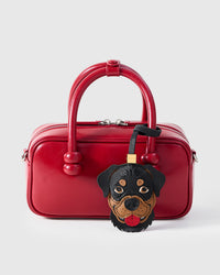 Handmade Rottweiler leather bag charm on a red leather handbag — built to last from full-grain French Alran goatskin, hand-layered, hand-stitched. STICKYZOO collectible.
