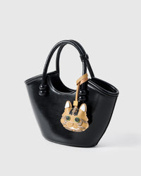 Forest Tabby charm on a glossy black bucket bag, side angle — rated 4.9★ by thousands of buyers. Real French Alran leather, 3 days by hand.
