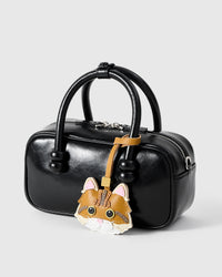 Ginger Maine Coon on a glossy black box bag, side angle — real French leather, 3 days by hand.