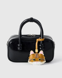 Ginger Maine Coon styled on a glossy black box bag, front — a small, specific piece that turns a simple bag into a personal one.