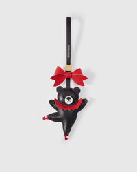 The Parisian Bear charm handmade from French Alran genuine goatskin — deep black bear mid-pirouette, red leather tutu, red ballet shoes, red bow at top, dark burgundy leather strap embossed with STICKYZOO. Three days by hand. Arrives in luxury gift packaging. Designed in Amsterdam.