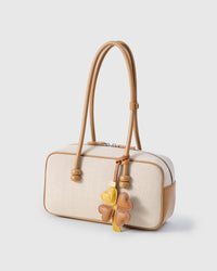 STICKYZOO Lucky Clover Charm clipped to a handbag — handmade French Alran goatskin in mustard yellow and tan. 3-day artisan build.