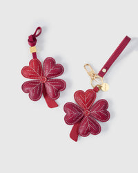 STICKYZOO Lucky Clover Charm clipped to a handbag — handmade French Alran goatskin in wine red. 3-day artisan build.