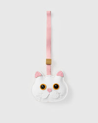 Snowy cat charm handmade from French Alran genuine goatskin — pure ivory body, pink inner ears, vivid gold-orange eyes, pink nose, soft pink leather strap. Three days by hand. Arrives in luxury gift packaging. Designed in Amsterdam.