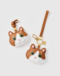Both editions of the patchwork cat side by side — leather strap loop for bags, or 18K gold-plated keychain clip with engraved STICKYZOO disc.