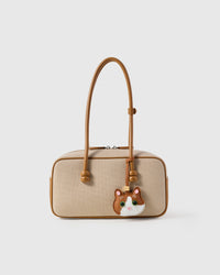 Patchwork cat charm styled on a cream canvas-and-tan top-handle bag, front — a small, specific piece that turns a simple bag into a personal one.