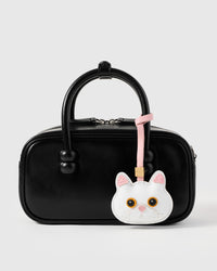 Snowy cat styled on a glossy black box bag, front — a small, specific piece that turns a simple bag into a personal one.