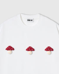 Detail of hand-stitched mushroom trio showing dimensional texture and polka-dot cap pattern