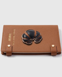 Croissant charm detail showing hand-layered brown and tan leather folds on STICKYZOO A5 notebook