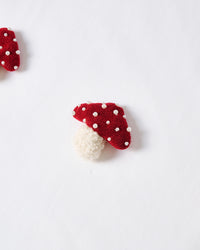 Close-up of plush mushroom applique showing red spotted cap and cream stem on white cotton
