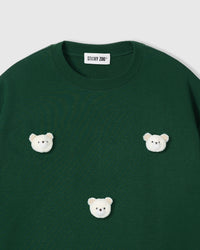 Close-up of white plush bear faces with gingham ears on green cotton
