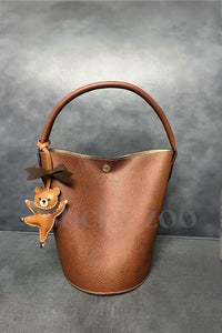 Both editions of the ballet bear charm — leather strap loop for bags, or 18K gold-plated keychain clip.