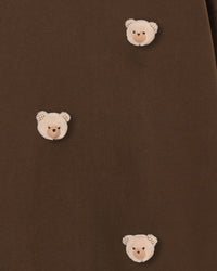 Multiple bear faces on dark brown fabric showing checkered ear pattern and dimensional plush