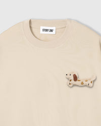 Close-up of spotted dachshund plush on beige cotton showing tonal cream body and brown spots