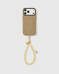 Full phone with the ivory teddy heart strap clipped on, hanging from the base of a black phone case.