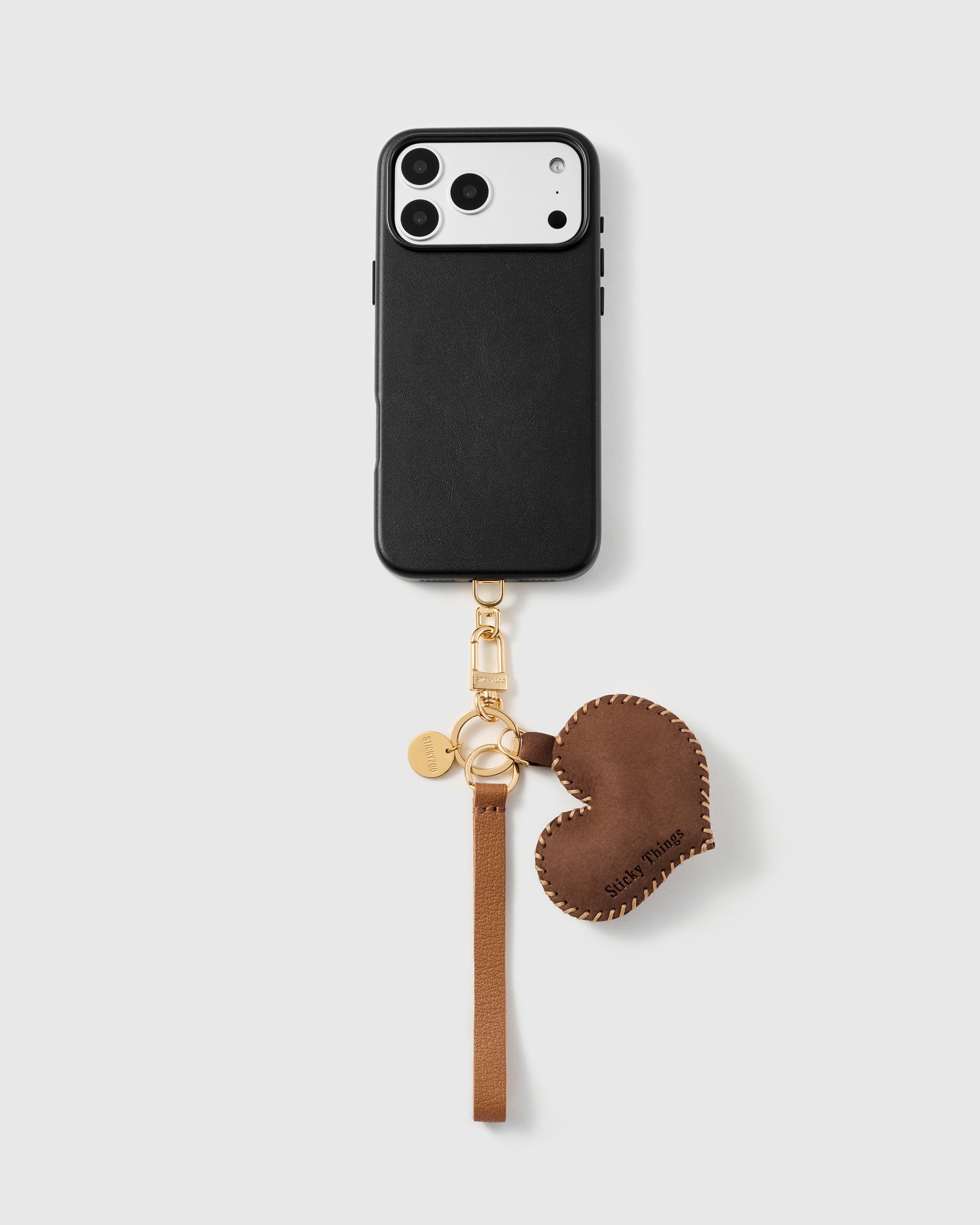 Cocoa leather heart phone strap clipped to a black phone case, worn hands-free from the wrist