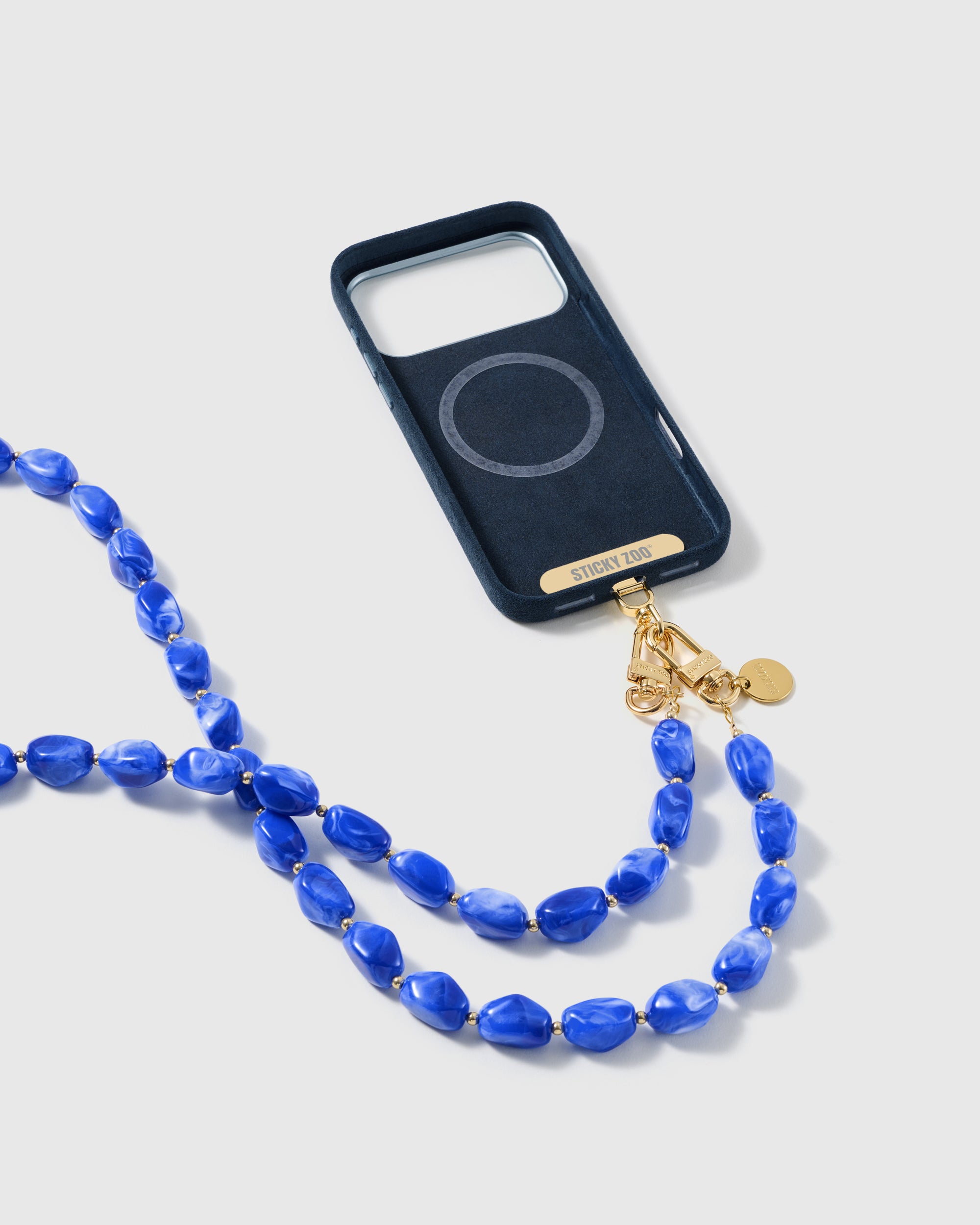 Full phone fitted with the long cobalt-blue beaded cross-body strap in a studio shot