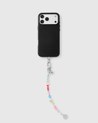 Colorful charm phone strap hanging from black phone case showing wrist carry functionality