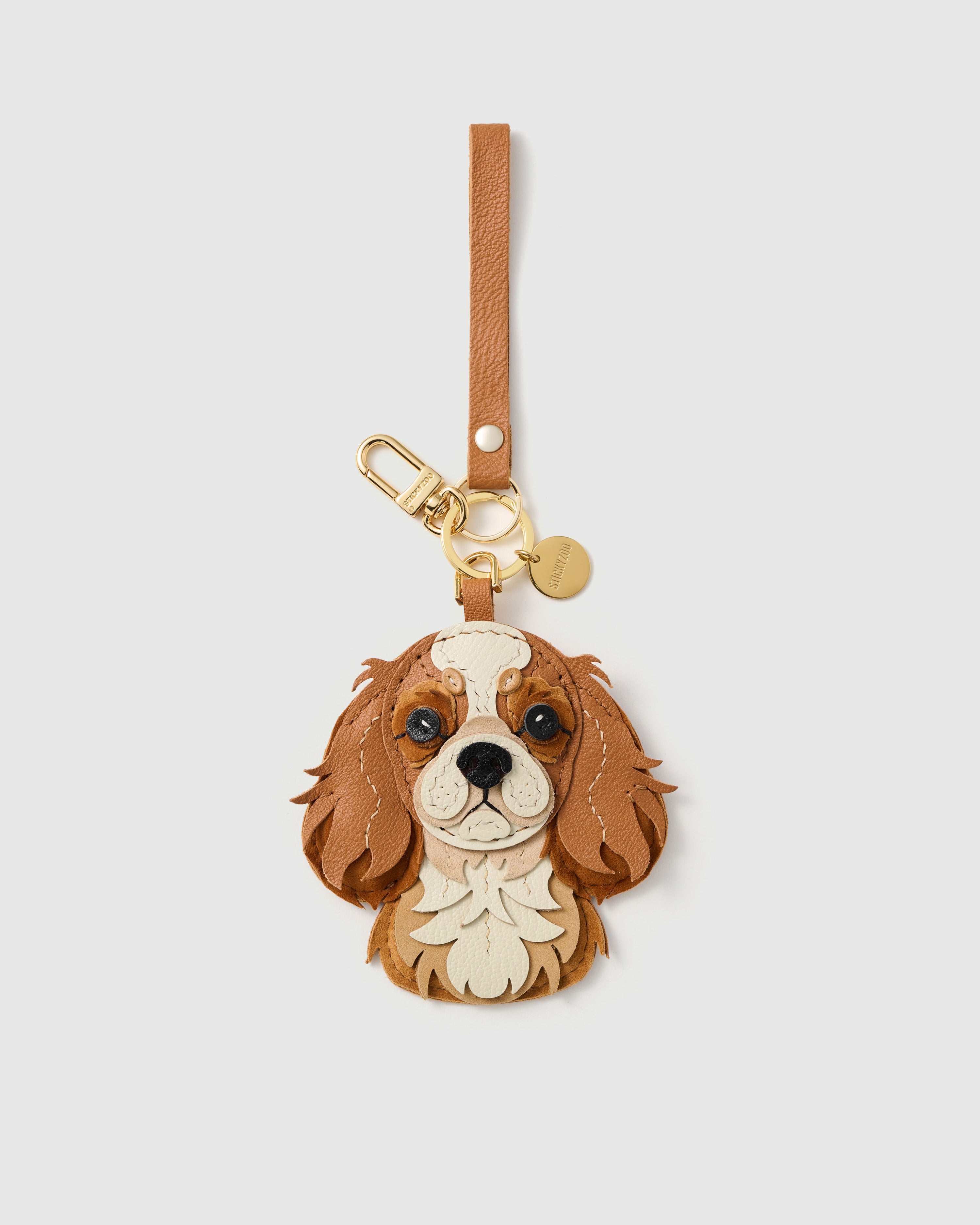{{Keychain edition.}} 18K gold-plated clip with engraved STICKYZOO disc — Cavalier King Charles in French Alran goatskin and alcantara suede. Designed in Amsterdam.